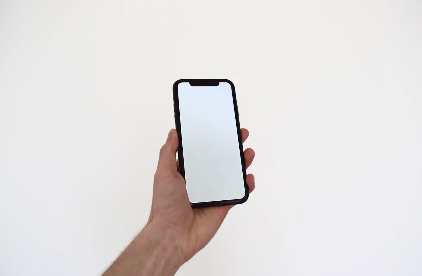 A hand holding up a phone with a blank white screen