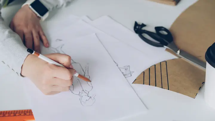 A hand sketching a design on paper