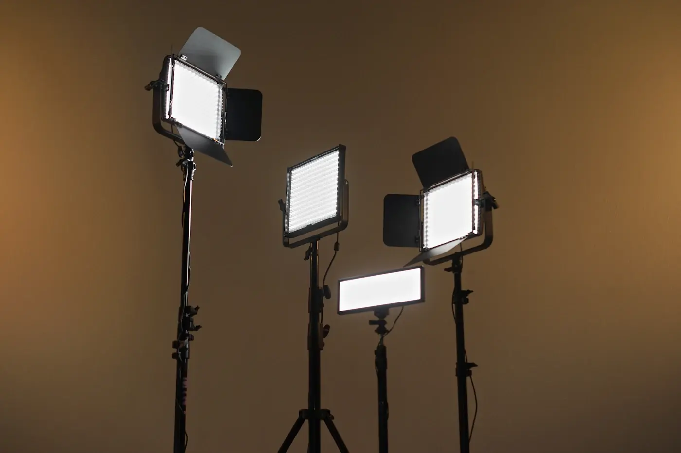 Three studio lights on stands against a dark wall
