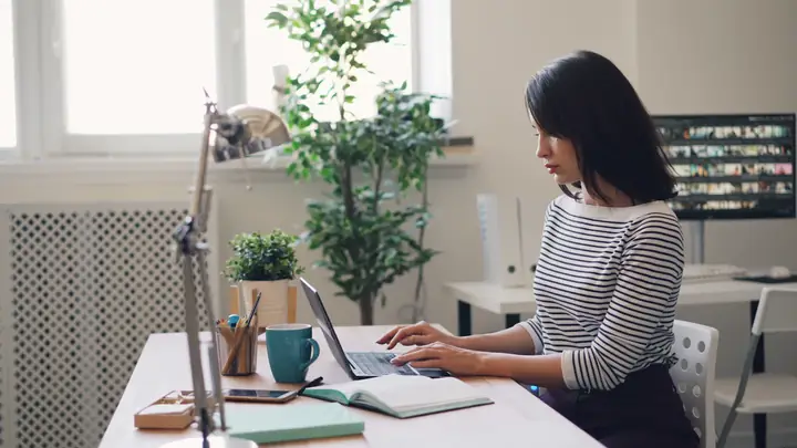 A woman working at a laptop by a window